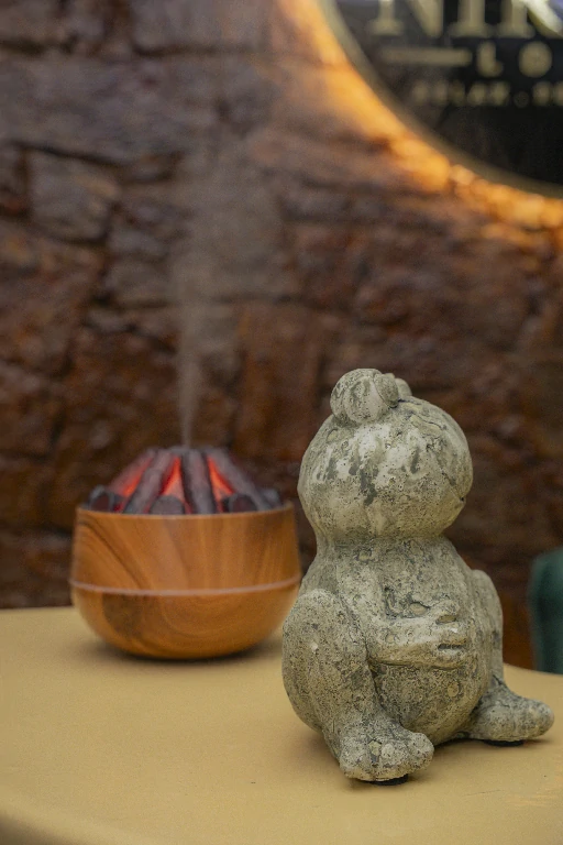 Wooden aroma diffuser beside a stone figure at Nirvana Lounge